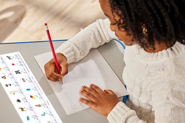 Student writing cursive on paper