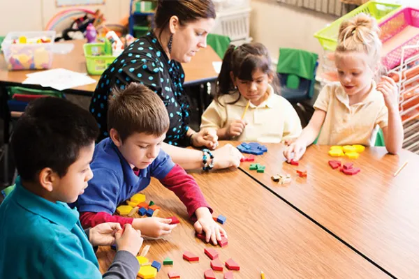 Students with teacher making shapes with pattern blocks