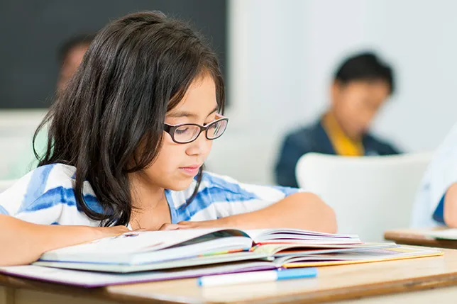 Student reading at desk in classroom