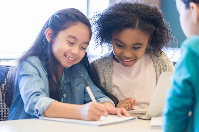 Three students writing and sharing stories