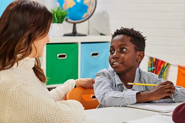 Student talking to a teacher seated next to him in math class