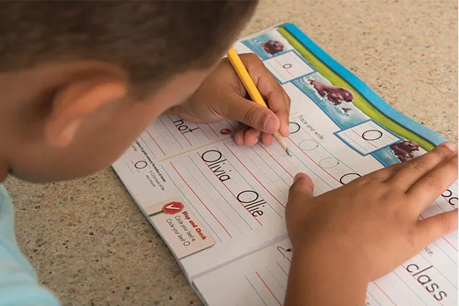 Left-handed student practicing the letter "O" in Zaner-Bloser Handwriting student worktext
