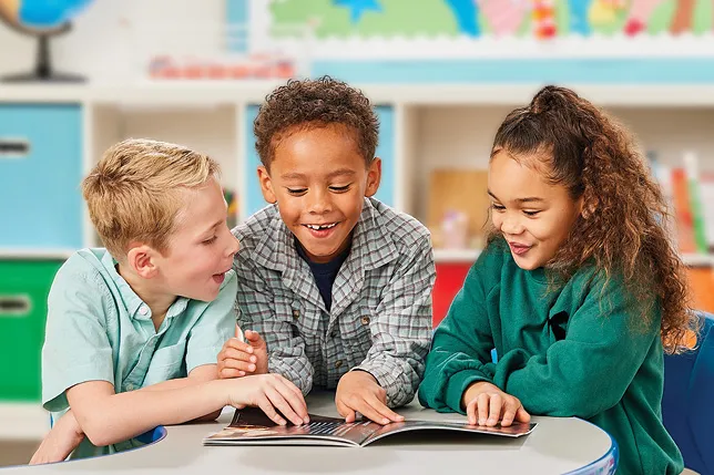 Three excited students read a Superkids Super Magazine together.