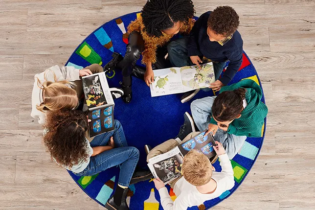 Students seated on a rug exploring books together