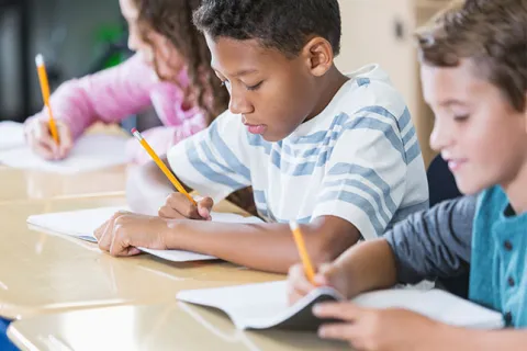 Row of students writing in worktexts at their desks