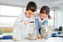 Two students investigate three glass jars filled with different numbers of objects