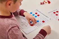Student covers numbers on a game board with red and blue dots
