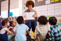 Teacher reading a book aloud to the class, pointing to page