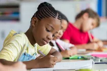 Students writing independently in notebooks inside a classroom